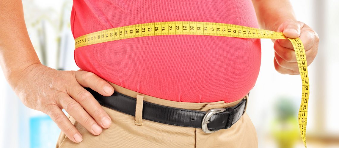Close-up on a man measuring his belly at home